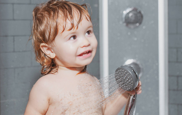 Funny happy baby bathes in bathtub with water and foam. Child bathing under a shower. Kids hygiene. - Foto, Bild