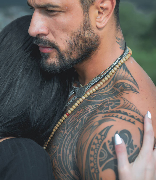 Σέξι και γυμνασμένη γυναίκα και αγκαλιάζει τον όμορφο άντρα με το τατουάζ. Πάθος και αισθησιακό άγγιγμα. Νεαρό ερωτευμένο ζευγάρι αγκαλιάζονται. Ρομαντικό και αγάπη. - Φωτογραφία, εικόνα