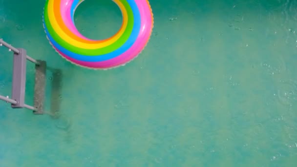 虹はプールでリングを泳いでいます。夏の天気. - 映像、動画