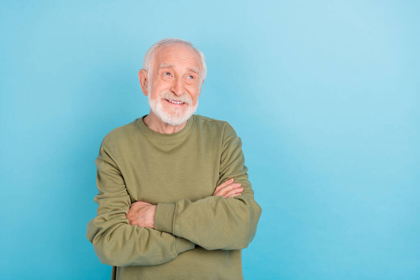 Portrait of attractive cheerful dreamy grey-haired man folded arms making decision isolated over bright blue color background - 写真・画像