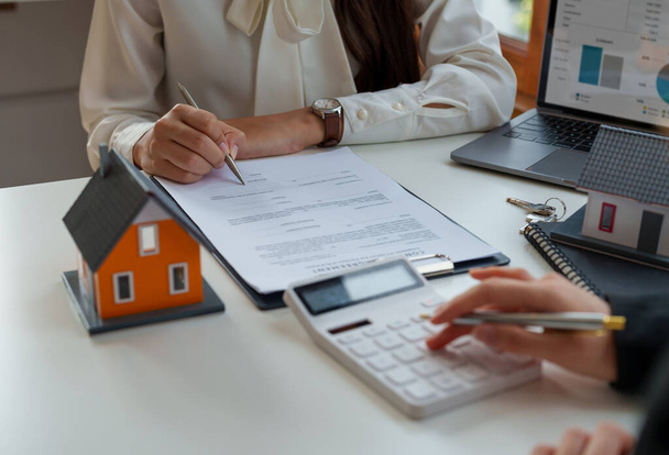 Immobilienmakler berechnen die Kreditwürdigkeit und raten Kunden, ihren Namen zu unterschreiben. Immobilienmakler, Immobilienmakler, Immobilien-Investment-Konzept - Foto, Bild