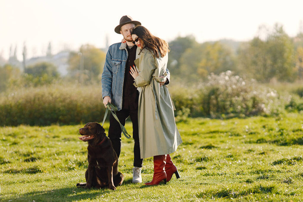 Stylish couple walking with a brown labrador on a nature - Foto, afbeelding