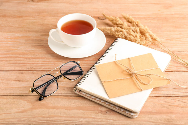 Composition with eyeglasses, cup of tea and card on wooden background - 写真・画像