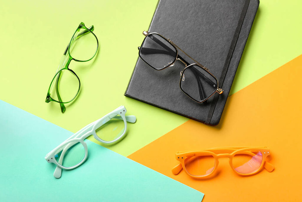 Set of eyeglasses and notebook on color background - Photo, Image