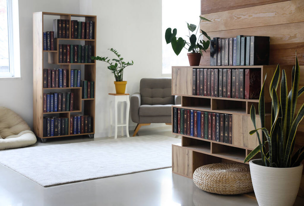 Interno di soggiorno luminoso con librerie in legno e piante d'appartamento - Foto, immagini