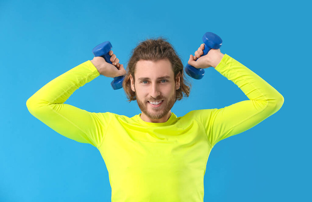 Uomo sportivo con manubri su sfondo blu - Foto, immagini