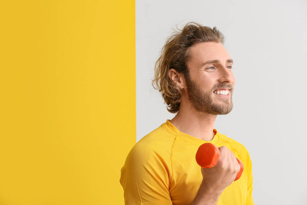 Спортивный человек с гантели на цветном фоне - Фото, изображение