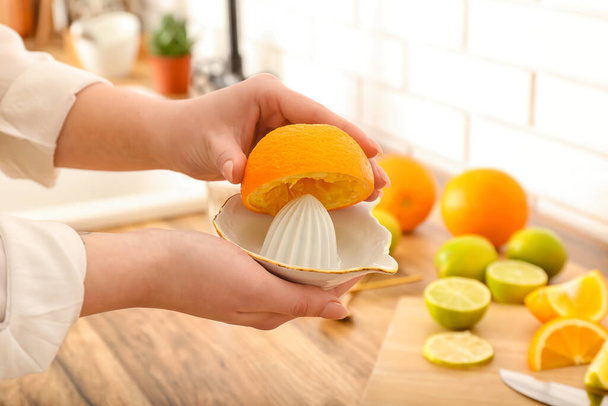 Woman squeezing orange for juice in kitchen, closeup - Fotó, kép