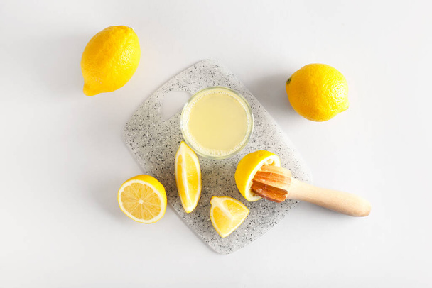 Olgun limonlu kompozisyon, meyve sıkacağı ve açık arkaplanda bir bardak meyve suyu. - Fotoğraf, Görsel