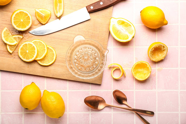 Composition with ripe lemons and juicer on color tile - Fotoğraf, Görsel