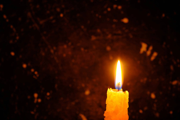 Candle burning brightly against dark wall - Фото, изображение
