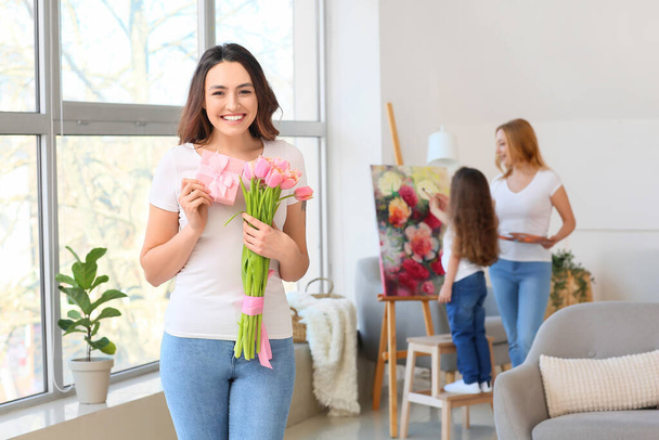 Giovane donna con fiori e regalo per la Giornata internazionale della donna a casa - Foto, immagini