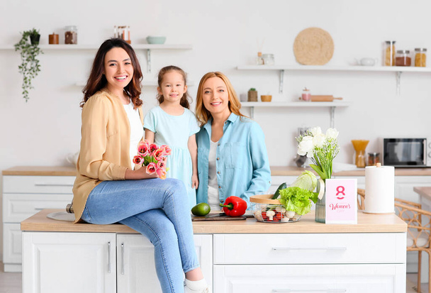 Gelukkige jonge vrouw, haar dochtertje en moeder in de keuken thuis. Internationale Vrouwendag viering - Foto, afbeelding