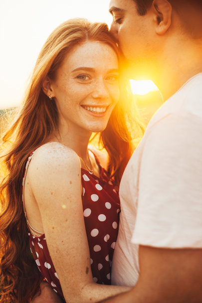 Gros plan portrait de garçon embrassant le front de sa petite amie rousselée pendant la promenade d'automne dans le champ de blé doré. Famille heureuse. - Photo, image