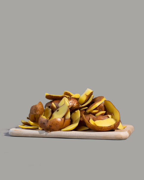 Concepto de detener el día de desperdicio de alimentos. Las cáscaras de patata son uno de los artículos más comúnmente descartados durante la preparación de alimentos. Fondo gris. - Foto, Imagen