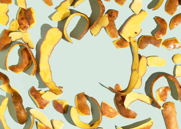 Concept van Stop voedselverspilling dag. Aardappelschillen zijn een van de meest voorkomende afgedankte items tijdens de bereiding van voedsel. Patroon, platte lay, kopieerruimte - Foto, afbeelding
