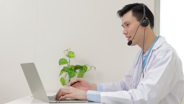 Azjatycki lekarz uśmiecha się pięknie Świadcząc usługi lecznicze dla pacjentów z rozmów online przez Internet na laptopach. Koncepcja lekarza online. Przestrzeń kopiowania - Materiał filmowy, wideo