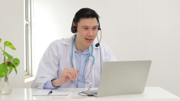 Azjatycki lekarz uśmiecha się pięknie Świadcząc usługi lecznicze dla pacjentów z rozmów online przez Internet na laptopach. Koncepcja lekarza online. Przestrzeń kopiowania - Materiał filmowy, wideo