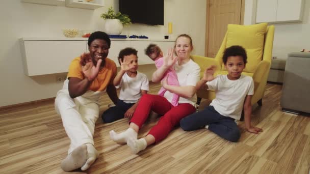 Multi raça família sentada no chão na sala e acenando com as mãos - Filmagem, Vídeo
