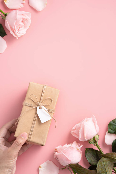 Mother's Day design concept background with pink rose flower and wrapped kraft gift box on pink table background. - Valokuva, kuva