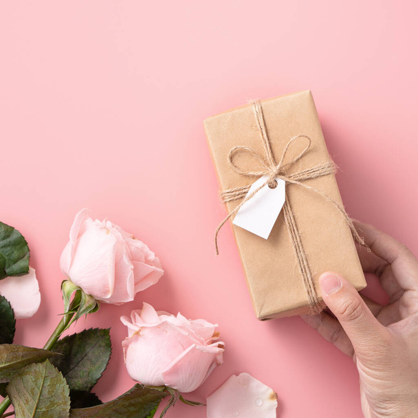Mother's Day design concept background with pink rose flower and wrapped kraft gift box on pink table background. - 写真・画像
