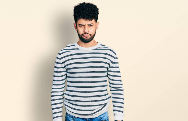 Young arab man with beard wearing casual striped sweater depressed and worry for distress, crying angry and afraid. sad expression.  - 写真・画像
