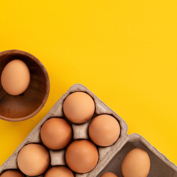 Top view of fresh brown chicken eggs isolated on yellow table background - Foto, afbeelding
