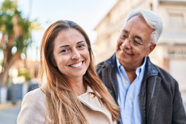 mężczyzna i kobieta w średnim wieku para uśmiecha się pewnie stojąc razem na ulicy - Zdjęcie, obraz