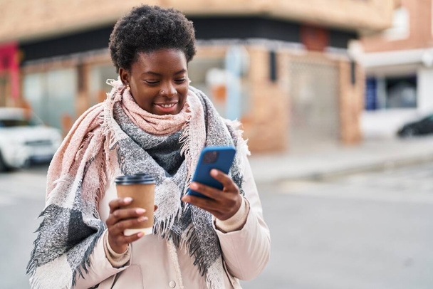 Mujer afroamericana usando smartphone bebiendo café en la calle - Foto, Imagen