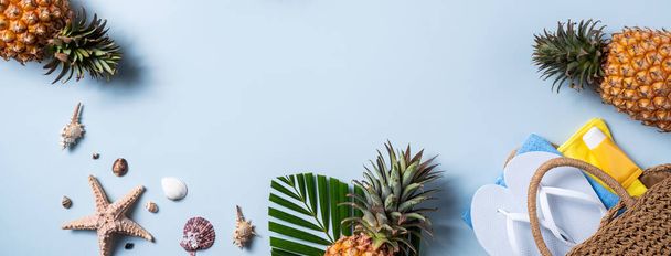 Summer fruit background design concept. Top view of holiday travel beach with shells, hat, pineapple and palm leaves on blue background. - Foto, afbeelding