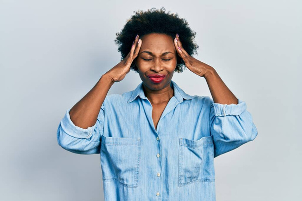 Jonge Afro-Amerikaanse vrouw draagt casual kleding die lijdt aan hoofdpijn wanhopig en gestresst omdat pijn en migraine. handen op het hoofd.  - Foto, afbeelding