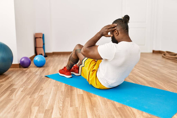 Νεαρός Αφροαμερικάνος στην πίσω όψη προπόνηση κοιλιακούς άσκηση στο αθλητικό κέντρο - Φωτογραφία, εικόνα