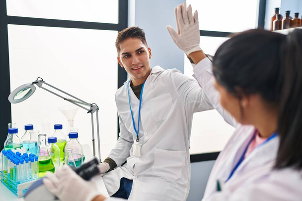 El hombre y la mujer científicos se asocian con High Five con las manos levantadas en el laboratorio - Foto, imagen