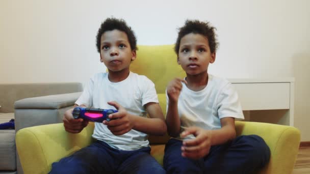 Dwóch czarnych chłopców bawi się w grę i zabiera sobie joysticka. - Materiał filmowy, wideo
