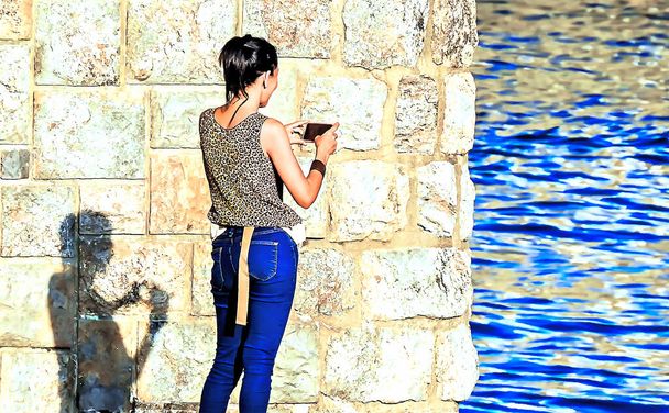 Jeune femme en jeans prenant des photos sur la jetée - Photo, image