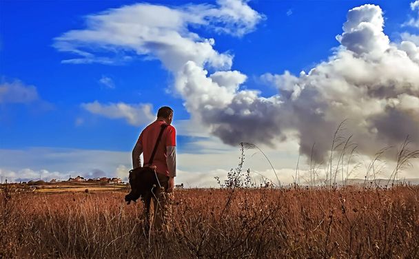 Aikuinen mies pellolla pilvinen taivas katselee kaukaisuuteen - Valokuva, kuva