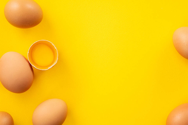 Top view of fresh brown chicken eggs isolated on yellow table background - Valokuva, kuva