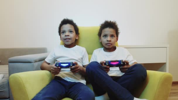 Δύο μικρά μαύρα αγόρια αδέλφια παίζουν ένα παιχνίδι χρησιμοποιώντας joysticks - Πλάνα, βίντεο