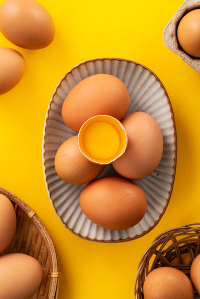 Top view of fresh brown chicken eggs isolated on yellow table background - Foto, imagen