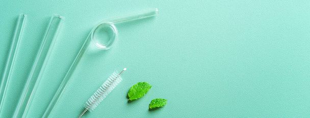 Reusable glass straw and cleaning brush set on green table background, design concept of environmental protection for Earth Day. - Photo, image