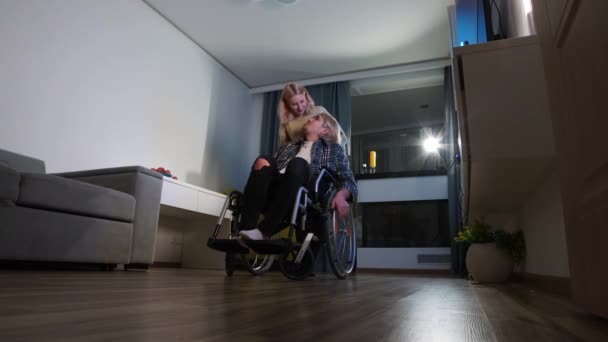 Mujer rubia besa a su novio en una silla de ruedas en su mejilla y saliendo de la habitación - Imágenes, Vídeo