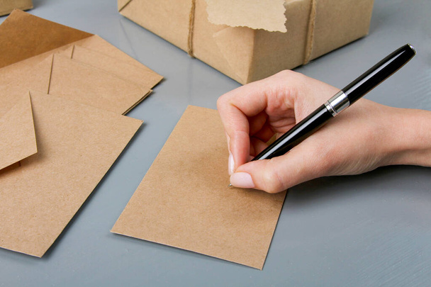 kobieta do podpisania koperty na listy na szarym drewnianym tle - Zdjęcie, obraz