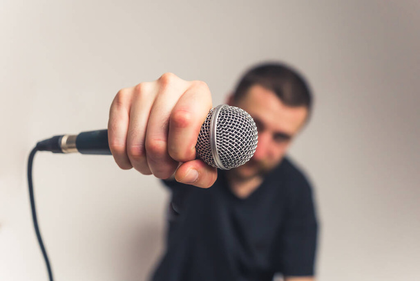 good-looking European young bearded man with mustache tattoos and microphone looking into the camera medium closeup studio shot light background - Φωτογραφία, εικόνα