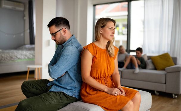 Sad pensive couple thinking of relationships problems sitting on sofa, conflicts in marriage, upset couple after fight dispute, making decision of breaking up get divorced - 写真・画像