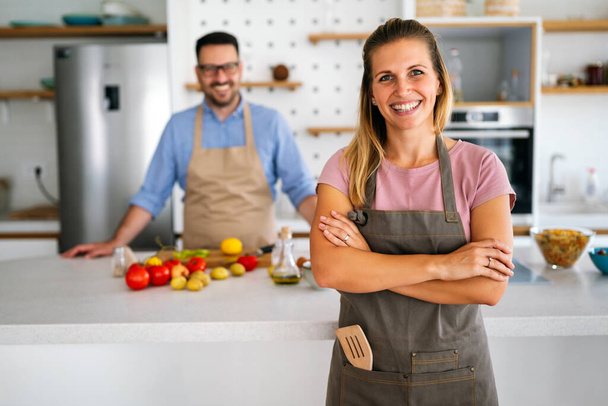 Young happy couple is enjoying and preparing healthy meal in their kitchen together. People food happiness concept. - Valokuva, kuva