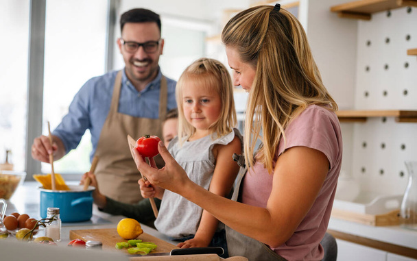Happy young family preparing healthy food together in kitchen. People happiness cooking concept - Fotoğraf, Görsel