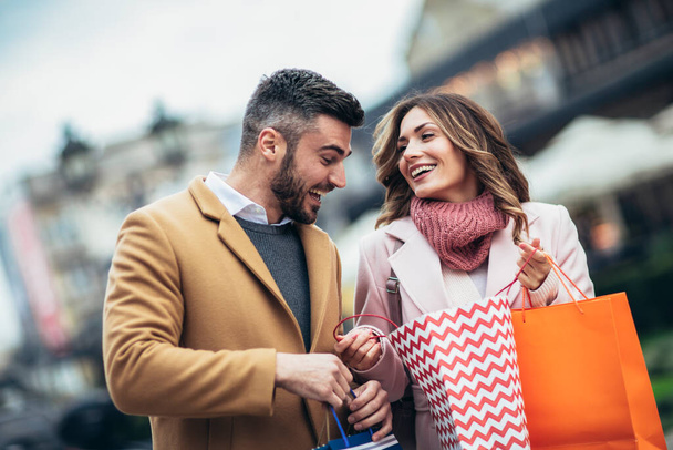 Ein Touristenpaar, das in einer Straße der Stadt spaziert und zusammen einkauft. Menschen kaufen Spaß Konzept - Foto, Bild