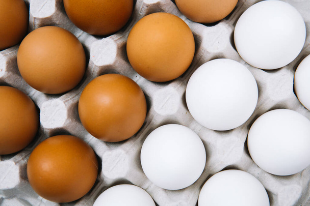 Yumurta kutusunda düz beyaz ve kahverengi yumurtalar. Taze tavuk yumurtası. Üst manzara doğal organik yumurta. Sağlıklı gerçek yemek. - Fotoğraf, Görsel