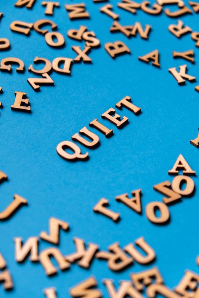 Wort QUIET aus Holzbuchstaben auf hellblauem Hintergrund. Motivationsworte Zitate Konzept. Inspirierende Phrase - Foto, Bild