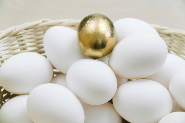 Raw white eggs and alone golden egg in a basket. White chicken eggs in turn top view - Фото, изображение